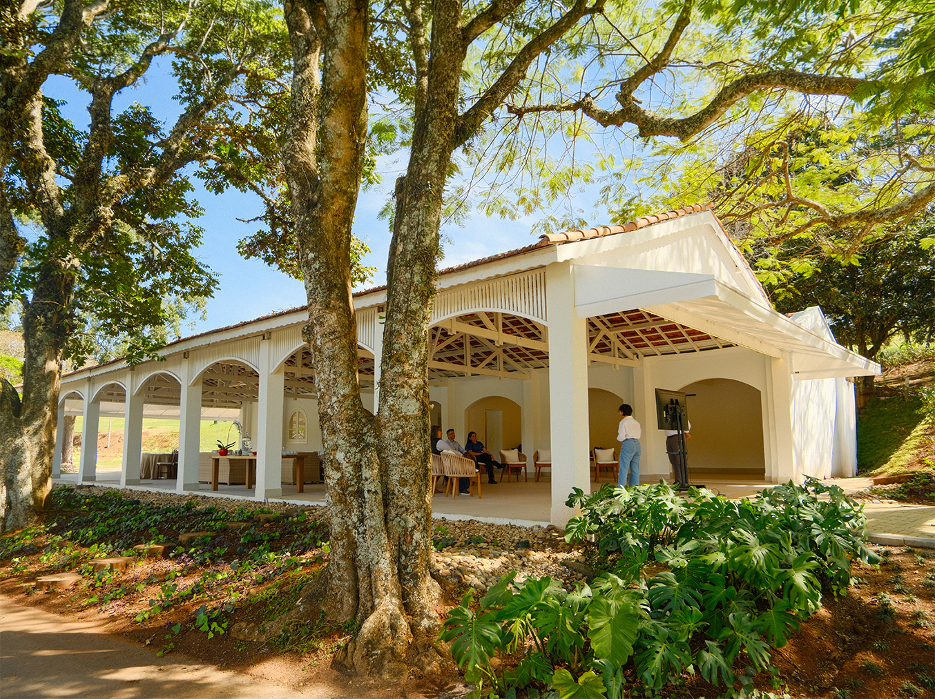 Fachada do salão Welcome, com arcos brancos e árvores ao redor